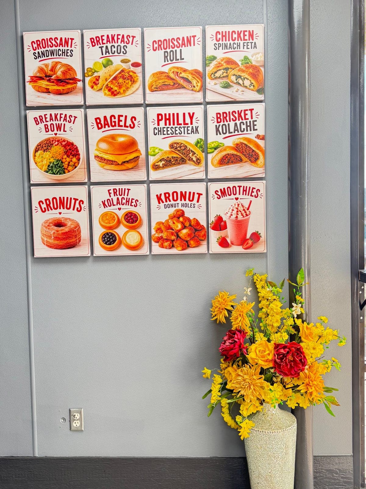 Inside BEST KOLACHE: a wall of menu posters beside a vase of yellow flowers