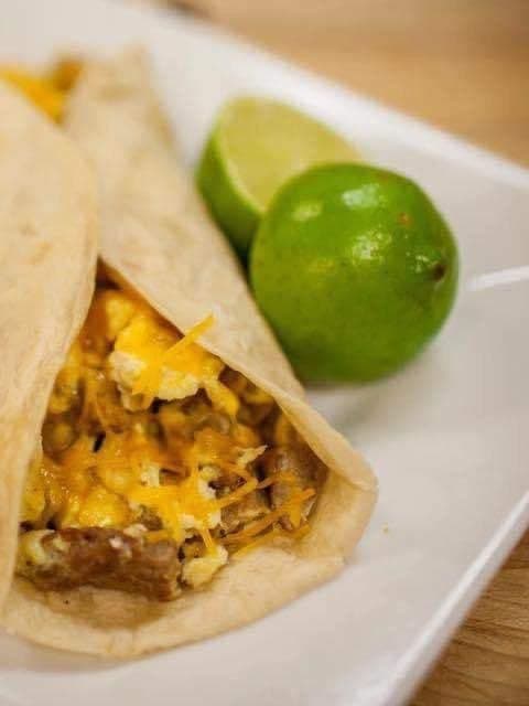 Sausage, egg and cheese breakfast taco with fresh limes